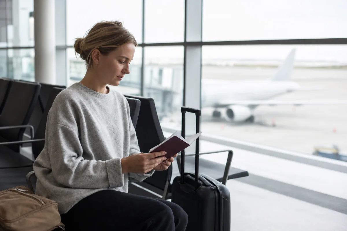 Resenär som väntar med resväska i en flygplatsterminal för artikeln Dina rättigheter som flygpassagerare